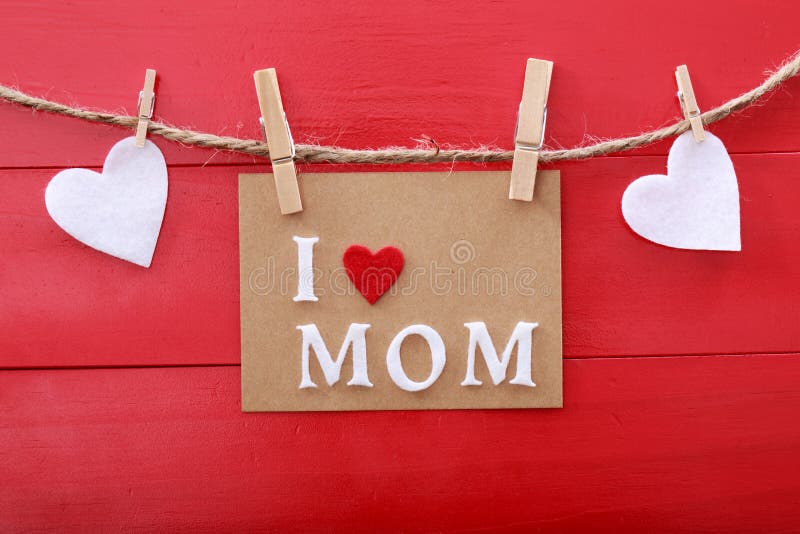 Mothers day message with felt hearts hanging with clothespins over red wooden board. Mothers day message with felt hearts hanging with clothespins over red wooden board