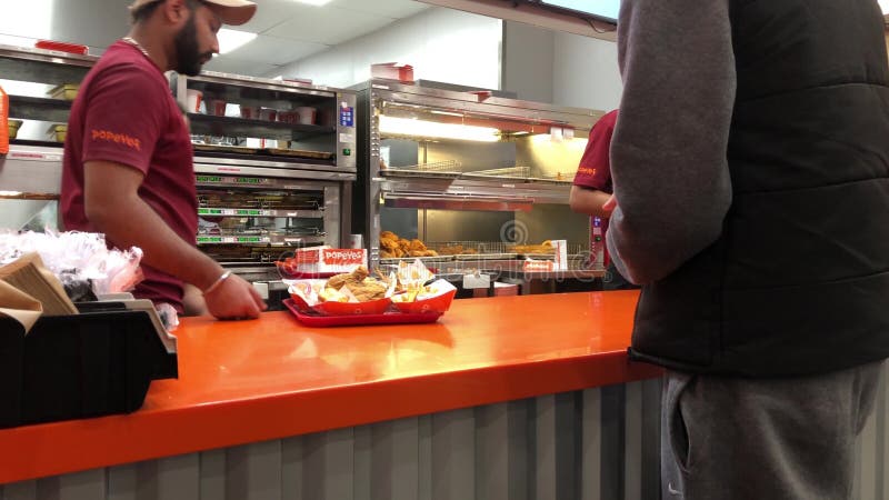 Motion of worker preparing food for customer inside Popeyes chicken restaurant