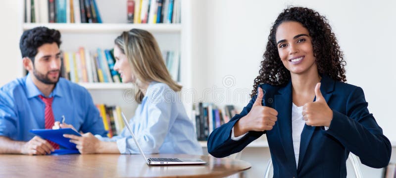 Motivated young hispanic businesswoman showing thumb up royalty free stock image