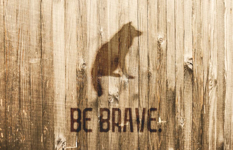 Motivatiekaart Zitting Wolf Burned in Houten Planken De tekst Moedig is stock fotografie Motivatiekaart Zitting Wolf Burned in Houten Planken De tekst Moedig is stock fotografie