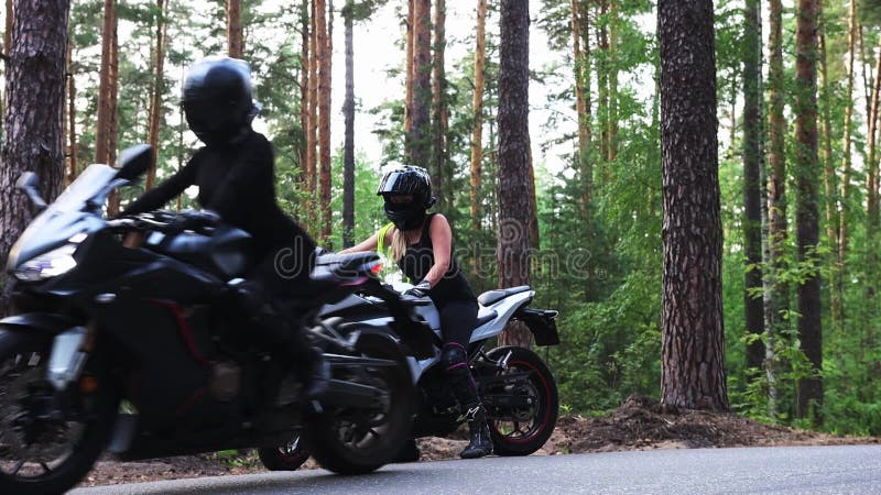 Motocicletas en el bosque dos mujeres adultas en cascos que comienzan un viaje en motocicletas en los bosques