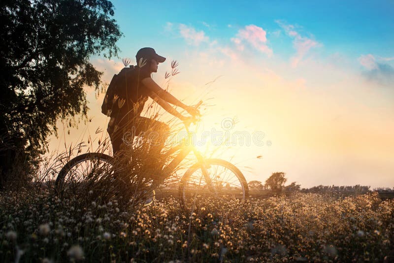 Motociclista sull'avventura del mountain bike in bella natura dei fiori del tramonto di estate