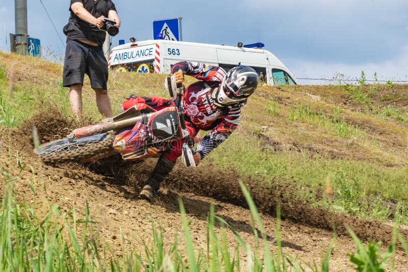 Motocross. Motorcyclist rushes along a dirt road, dirt flies from under the wheels. Photographers near. Doctors are watching. stock photo Motocross. Motorcyclist rushes along a dirt road, dirt flies from under the wheels. Photographers near. Doctors are watching. stock photo