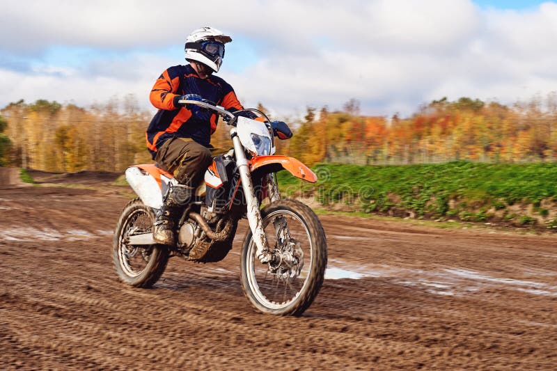 Motocrós, jinete del enduro en pista de tierra El bosque detrás de él foto de archivo Motocrós, jinete del enduro en pista de tierra El bosque detrás de él foto de archivo