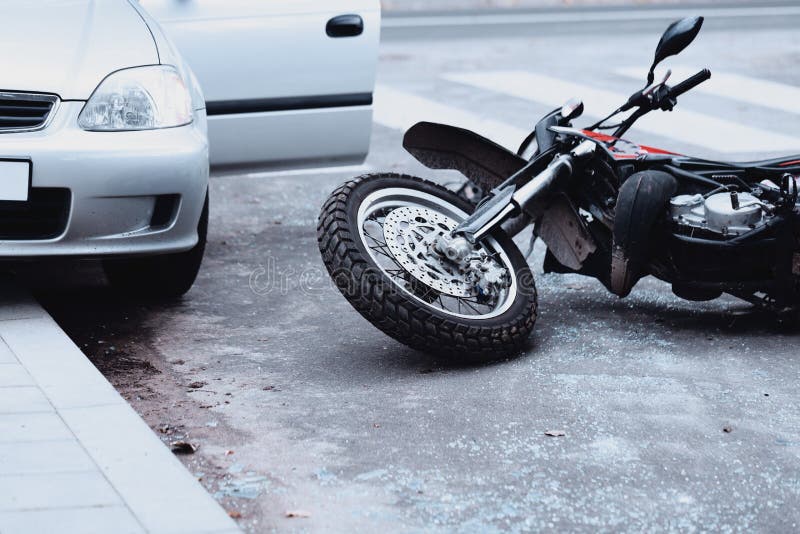 Motorcycle lying on the road and car standing with open door after a collision. Motorcycle lying on the road and car standing with open door after a collision