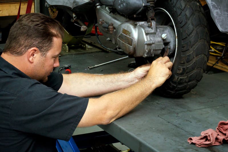 Motorcycle mechanic fixing rear tire stock photos