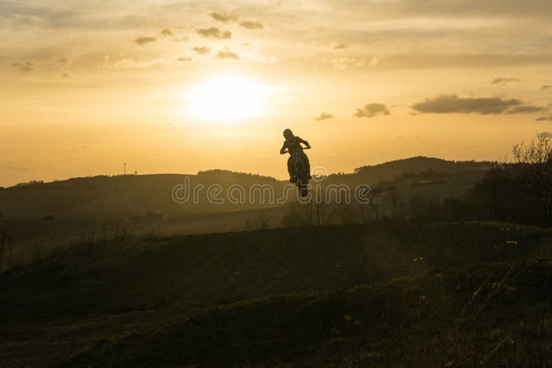 Motocyklista jazdiaci mimo cesty pri západe slnka. Slovensko