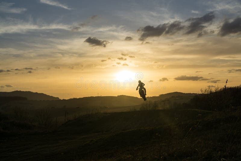 Motocyklista jazdiaci mimo cesty pri západe slnka. Slovensko