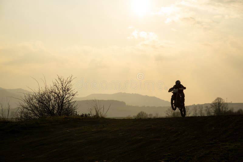 Motocyklista jazdiaci mimo cesty pri západe slnka. Slovensko