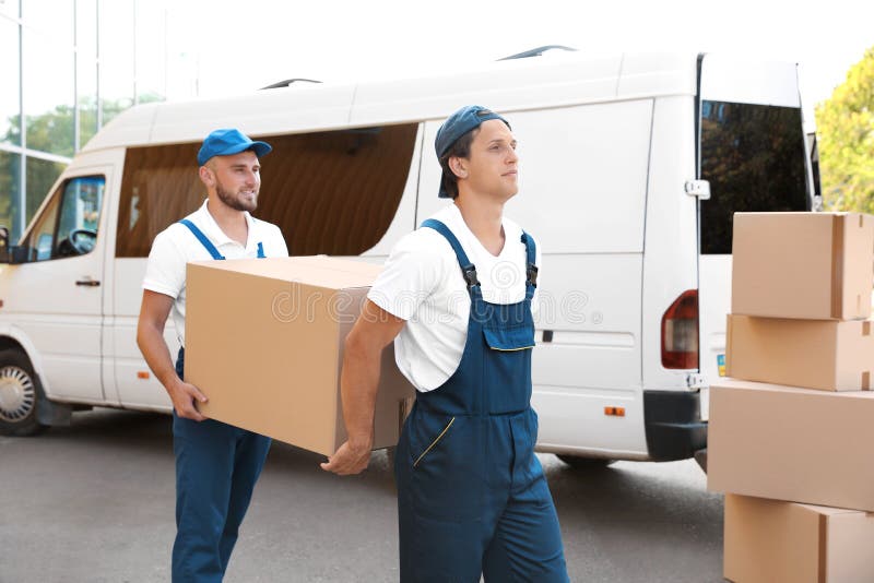 Motores masculinos que descargan las cajas de la furgoneta foto de archivo Motores masculinos que descargan las cajas de la furgoneta foto de archivo