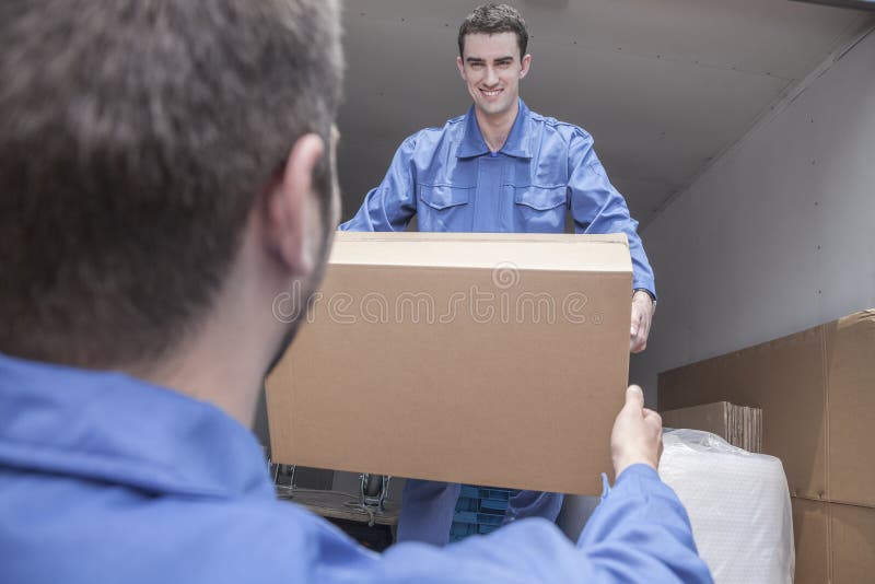 Motores que descargan una furgoneta móvil, pasando una caja de cartón foto de archivo libre de regalías Motores que descargan una furgoneta móvil, pasando una caja de cartón foto de archivo libre de regalías