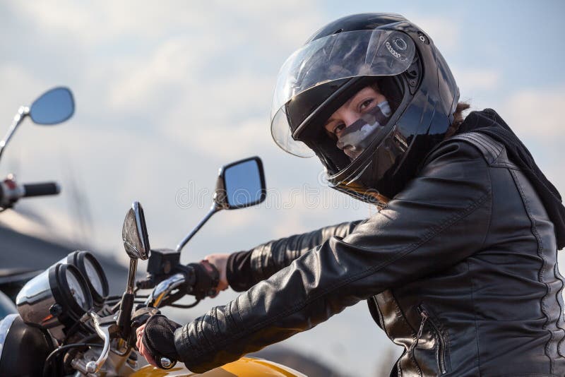 Motorfietsbestuurder in het zwarte stuurwiel van de uitrustingsholding en het bekijken camera, Kaukasische vrouw royalty-vrije stock fotografie Motorfietsbestuurder in het zwarte stuurwiel van de uitrustingsholding en het bekijken camera, Kaukasische vrouw royalty-vrije stock fotografie