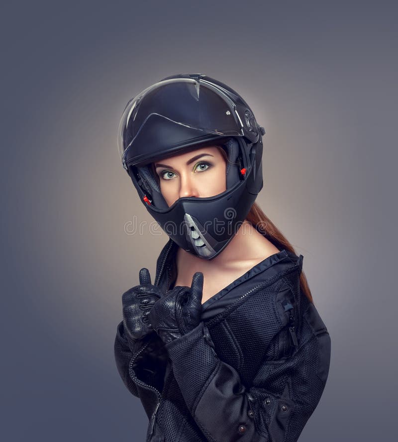 Motorista de la muchacha en una chaqueta negra y un casco fotografía de archivo libre de regalías Motorista de la muchacha en una chaqueta negra y un casco fotografía de archivo libre de regalías