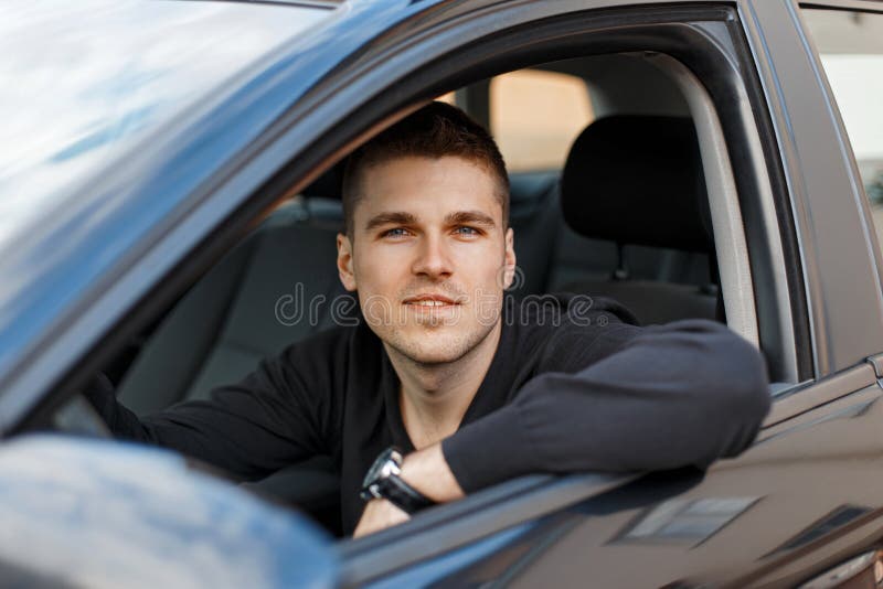 Motorista masculino novo considerável em um carro preto imagem de stock Motorista masculino novo considerável em um carro preto imagem de stock