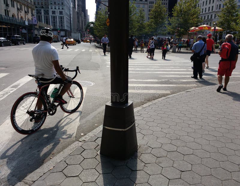 Motorista y peatones en la esquina de la 5ta avenida y de la plaza magnífica del ejército, cerca del Central Park, New York City, foto de archivo libre de regalías Motorista y peatones en la esquina de la 5ta avenida y de la plaza magnífica del ejército, cerca del Central Park, New York City, foto de archivo libre de regalías