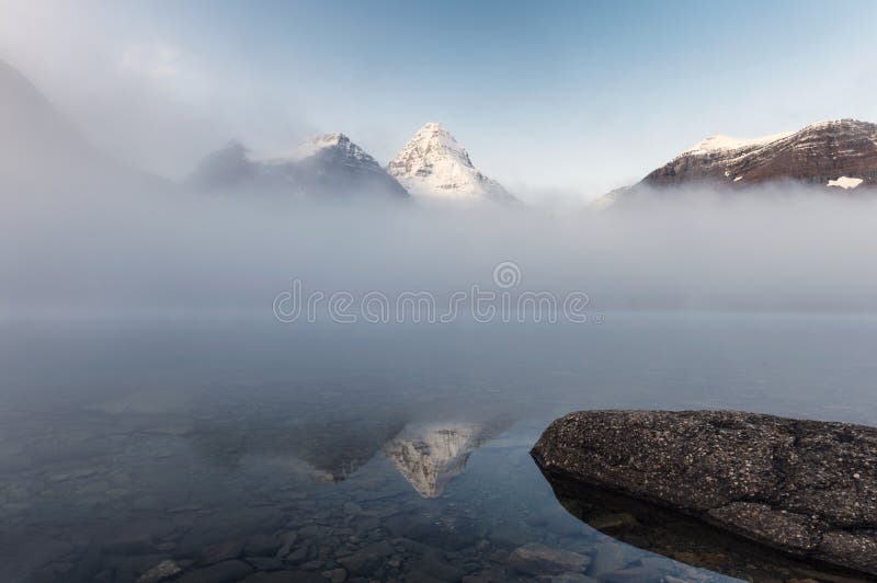 Mount Assiniboine in foggy on Magog lake in the morning at provincial park