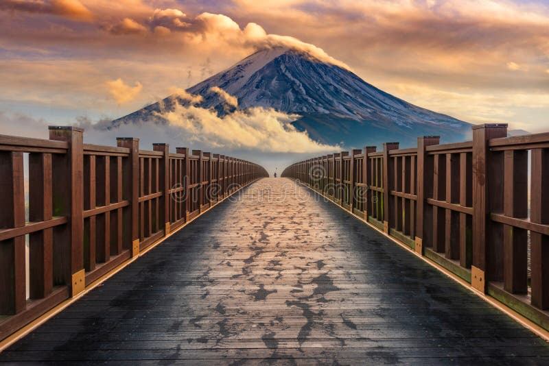 Mount Fuji with misty clouds passing by and a wooden bridge royalty free stock images