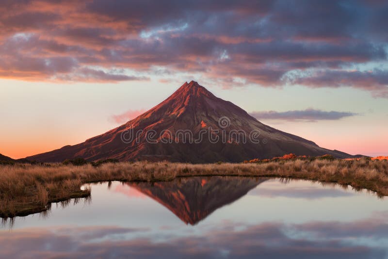 Mount Taranaki under the blue sky. Volcano Reflection on the Tarns Lake New Zealand in the Evening with Beautiful Sunset Colours.