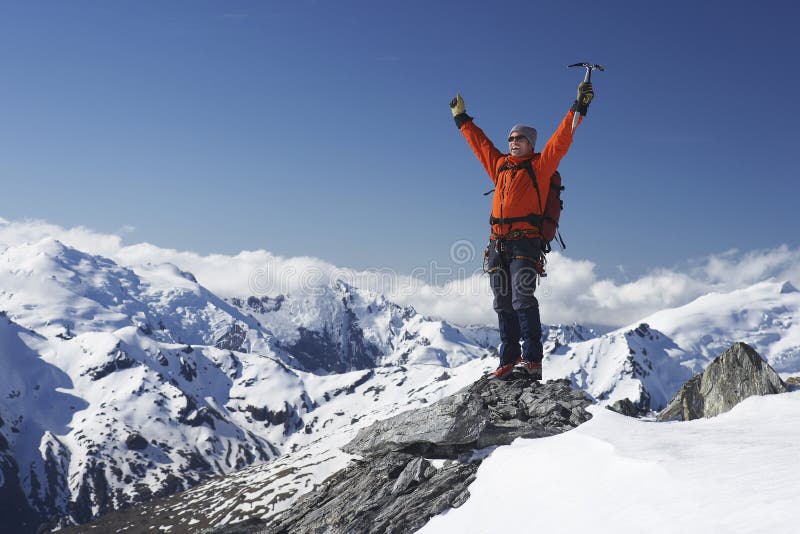 Male mountain climber raising hands with icepick on top of snowy peak. Male mountain climber raising hands with icepick on top of snowy peak