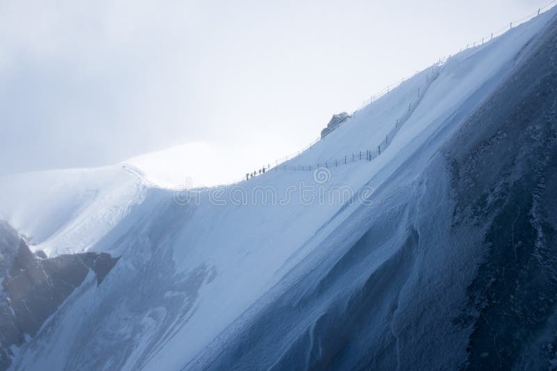 A group of mountain climbers on a ridge leading up to Aiguille du Midi, above Chamonix, in France. A group of mountain climbers on a ridge leading up to Aiguille du Midi, above Chamonix, in France