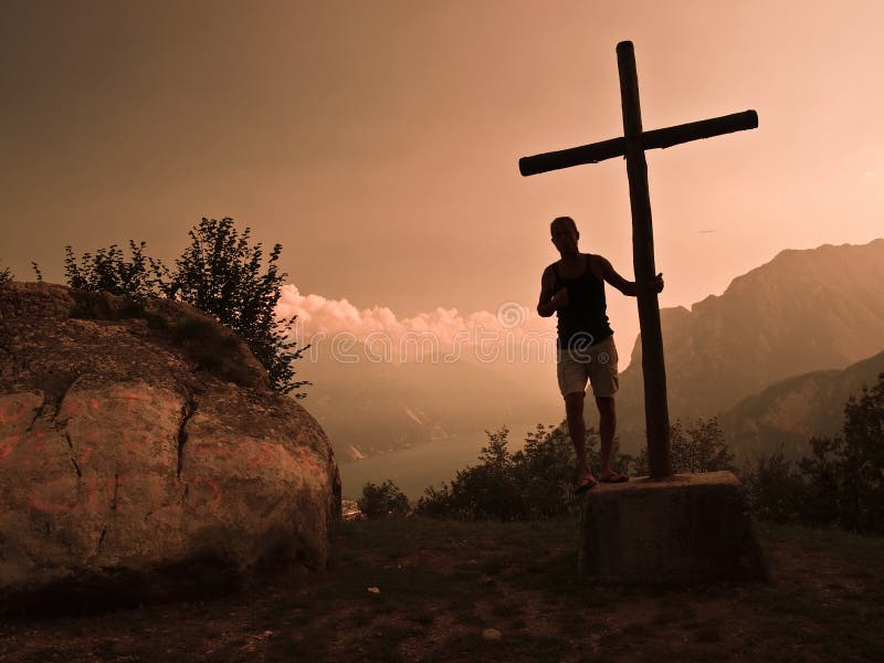 Silhouette of man supported by a mountain cross Lake Garda - italy as background