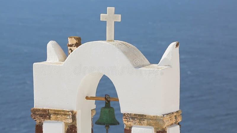 Mountain island rising up from water across sea, white arch with old rusty bell