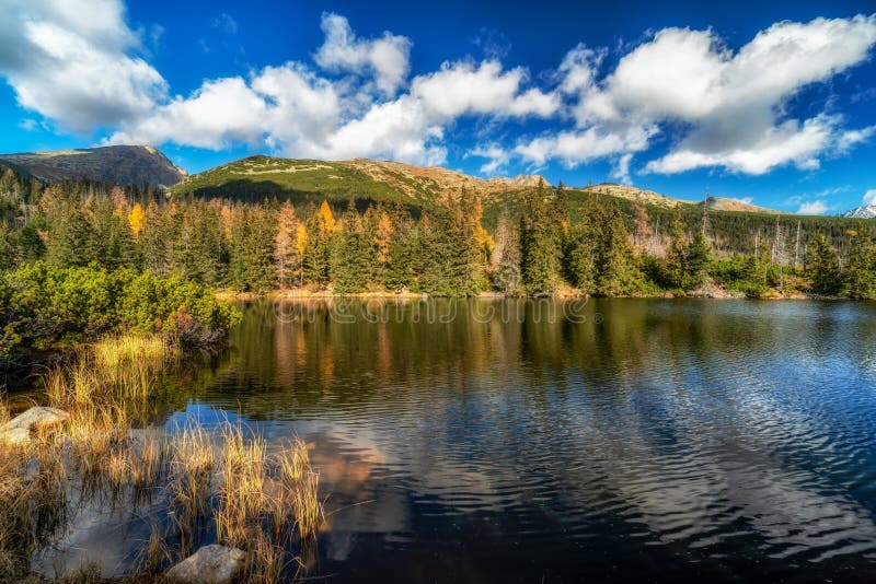 Horské jezero zvané Jamské pleso v barvách podzimu s vrcholem Kriváň v pozadí. Slovensko