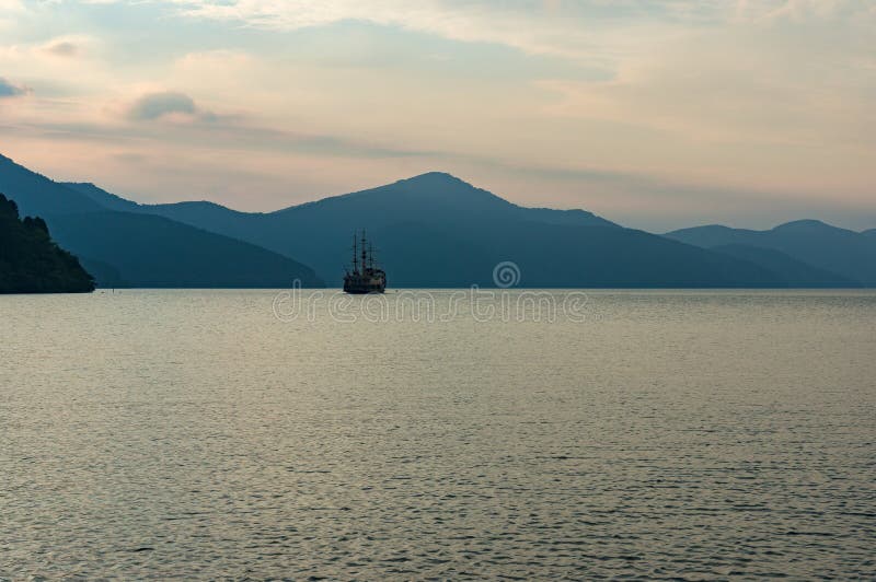 Mountain lake in dusk mist with old fashioned ship