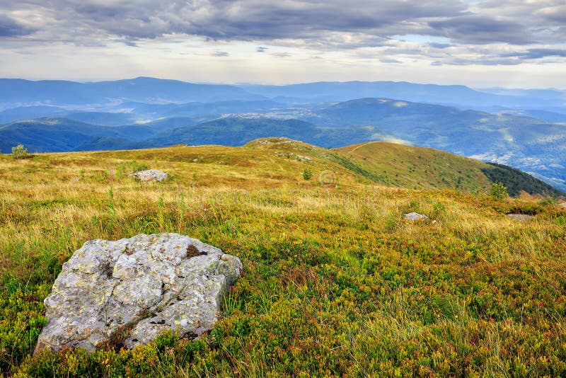 Mountain landscape with stones in the grass on hillside and blue