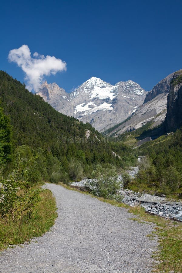 Mountain path with snowed peaks at background