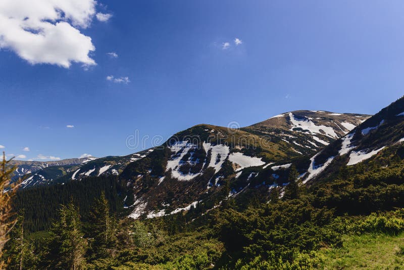 Horské štíty so zeleňou a snehom v Karpatoch
