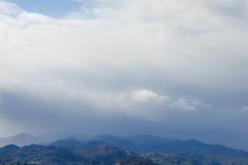 Mountain range in clear weather in contrasting rain clouds before the rain stock photo Mountain range in clear weather in contrasting rain clouds before the rain stock photo