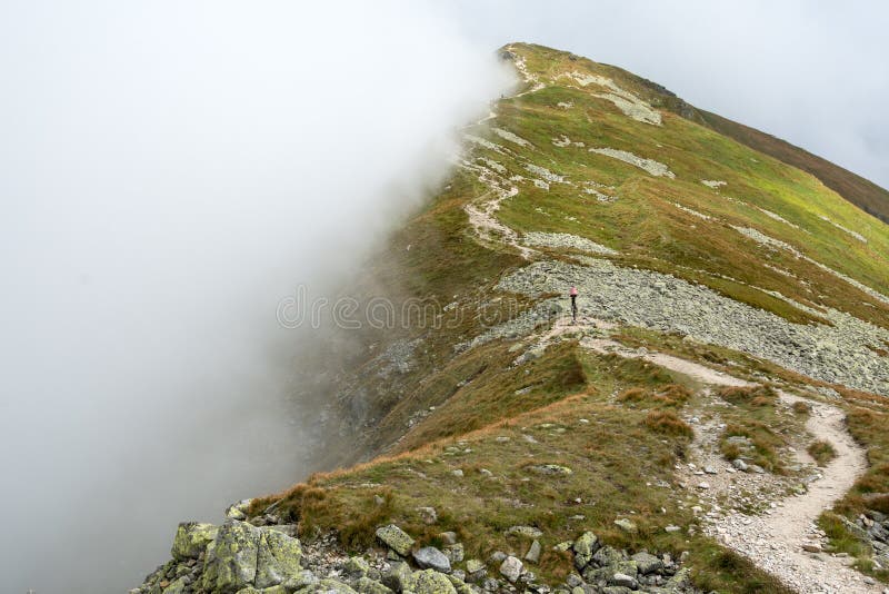 Mountain ridge covered by half with the cloud