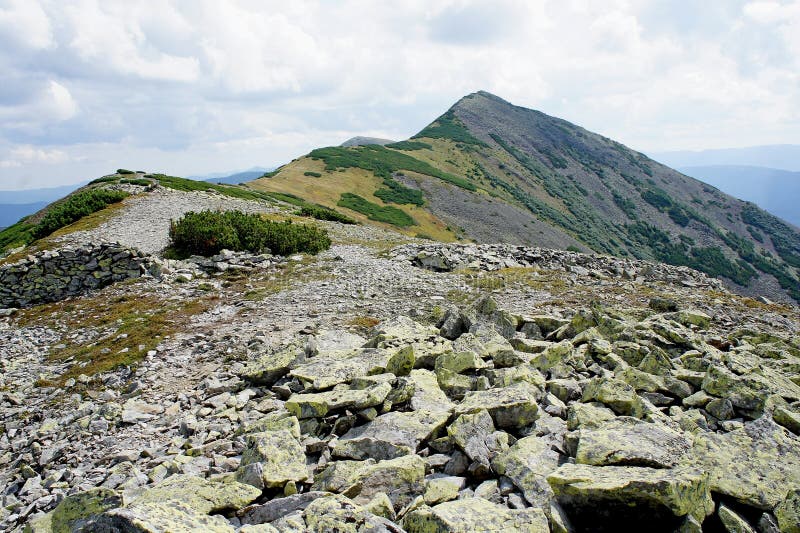 A mountain stone ridge with stones in the foreground and a sharp pyramidal top royalty free stock images