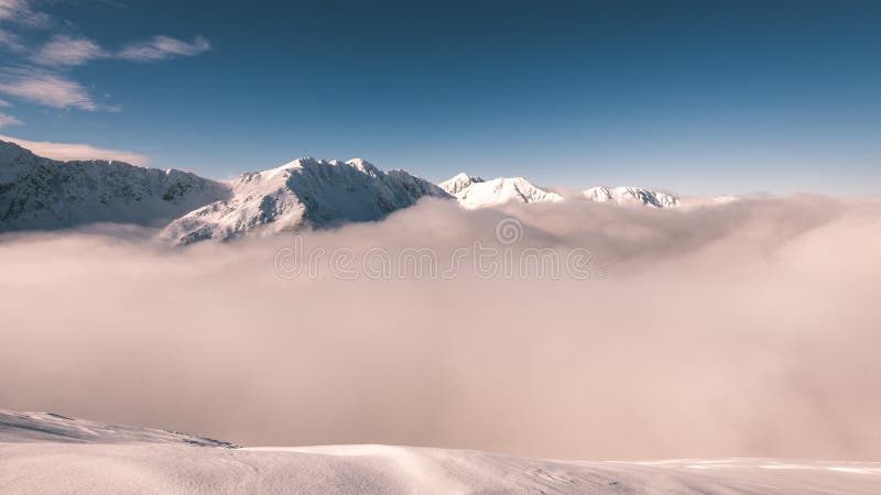 Mountain tops in winter covered in snow with bright sun and blue