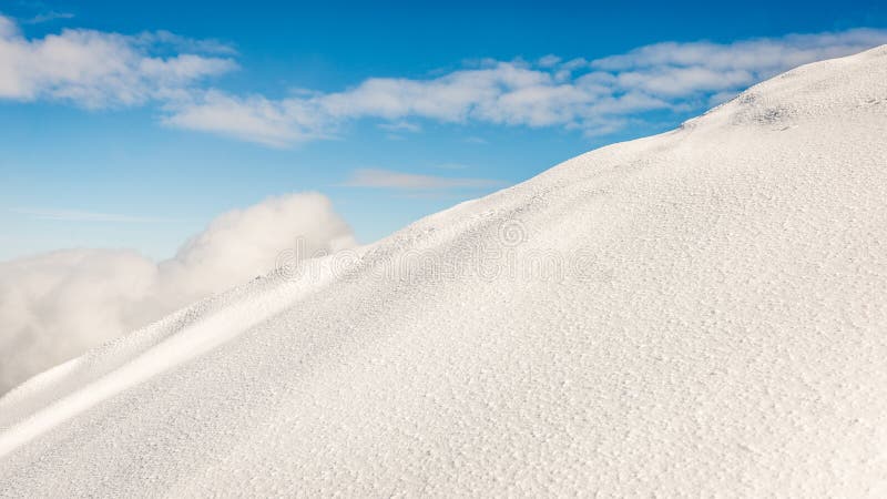 Mountain tops in winter covered in snow with bright sun and blue