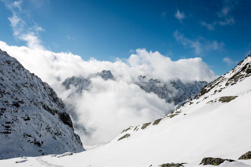 Mountain tops in winter covered in snow with bright sun and blue