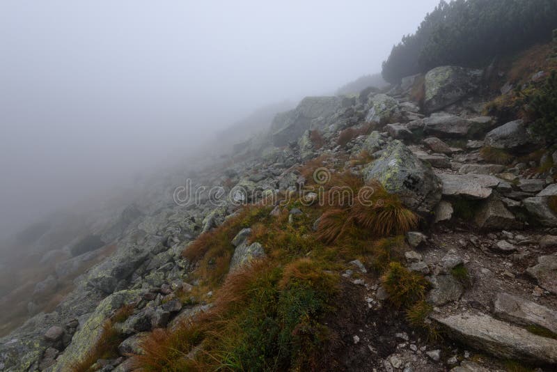 Mountain tourist trail in autumn covered in mist