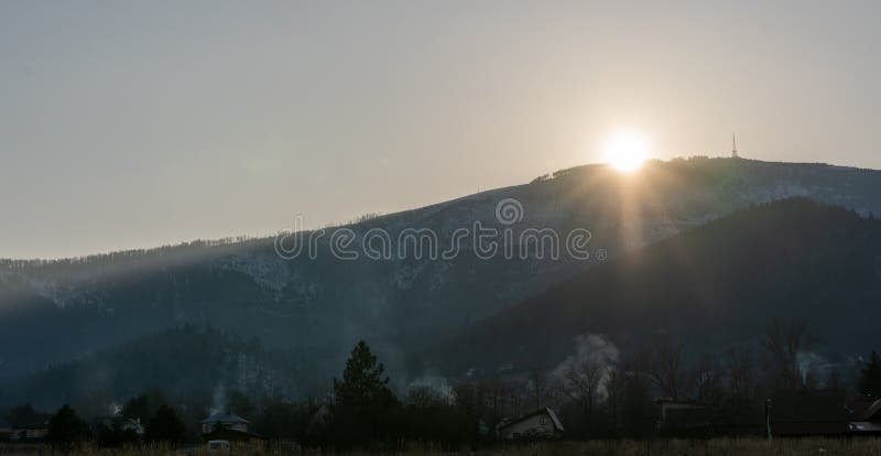 Výhled na hory s televizní anténou při západu slunce na obzoru