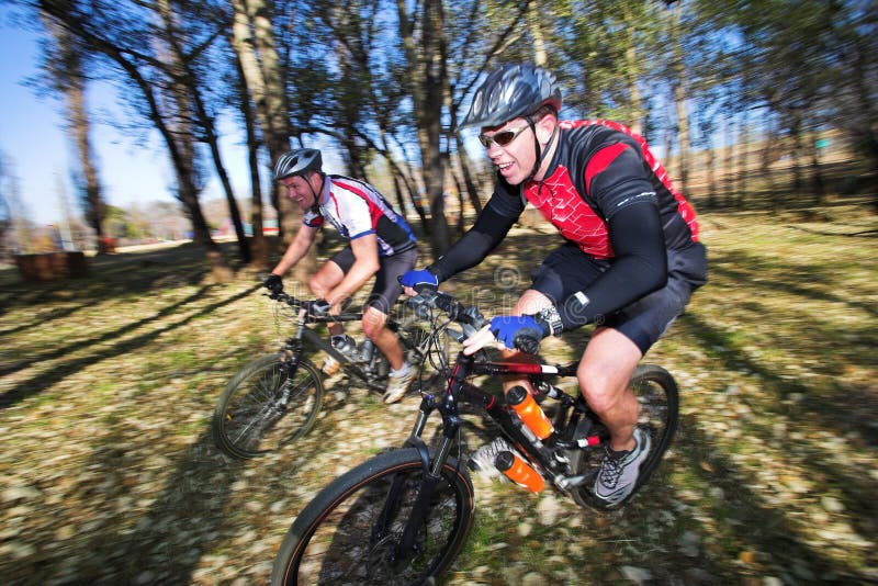 Scatto panoramico di due appassionati di mountain bike, corsa in un bosco.