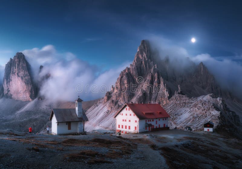 Mountains in fog with beautiful house and chapel at night