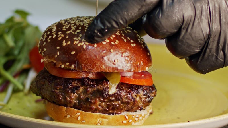 Mouvement lent d'hamburger de boeuf placé sur un petit pain banque de vidéos