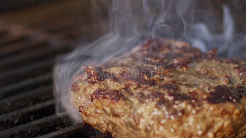 Mouvement lent d'hamburger de boeuf sur un gril dans la fin avec les flammes et la fumée clips vidéos