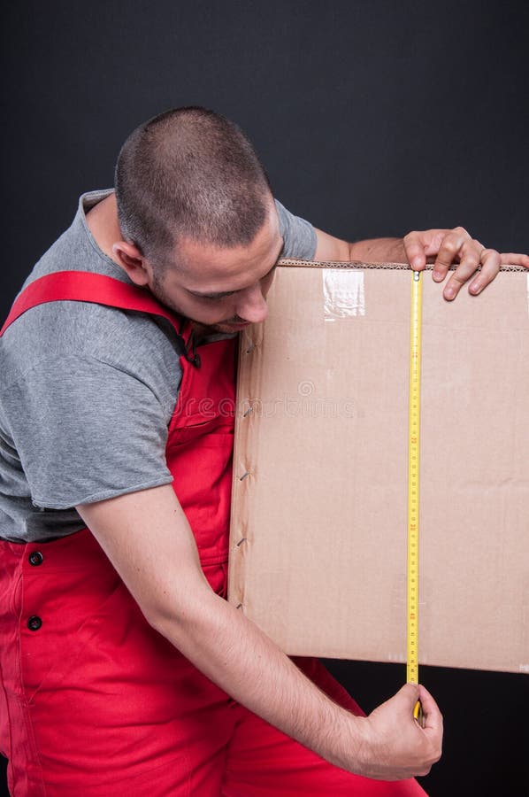 Mover guy holding box measuring with tape royalty free stock images