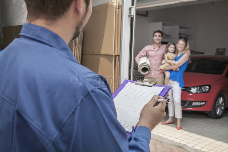 Mover holding clipboard and invoice, family in the background royalty free stock photos