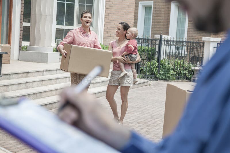 Mover holding clipboard and invoice, family in the background royalty free stock image
