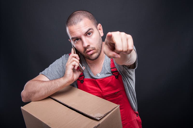 Mover man holding box talking at phone pointing camera royalty free stock images