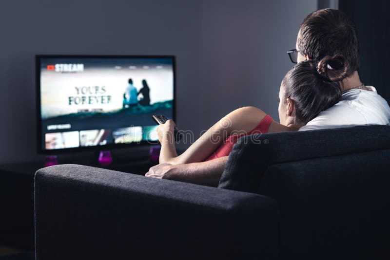 Movie stream service on smart tv. Couple watching series online. Woman choosing film or new season with remote control.