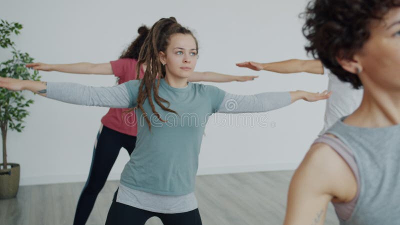 Movimento lento do grupo de jovens treinando com instrutor em estúdio de yoga