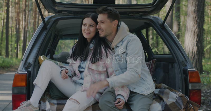 Movimiento lento de hombres y mujeres que hablan apuntando a un hermoso bosque sentado en un auto disfrutando de un viaje por carr